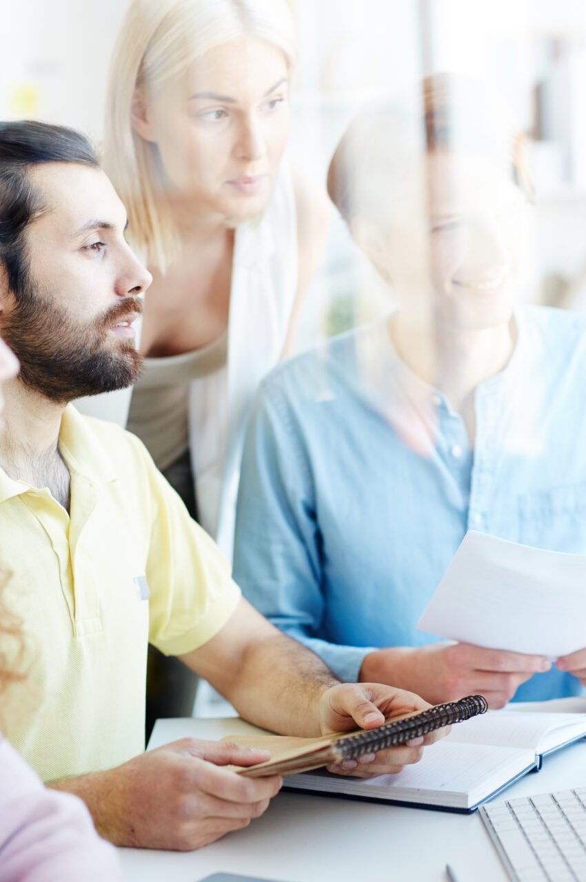 Group of four creative people watching webcast for designers while sitting in front of computer monitor